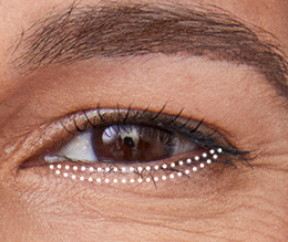 Extreme close up of a hooded eye with dotted outline for eyeshadow placement beneath lower lashes.
