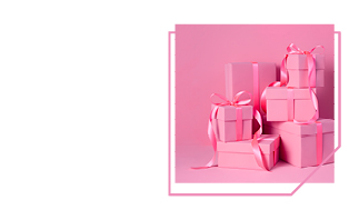 In pinkem Geschenkpapier eingepackte Geschenke stehen getürmt vor einem rosa Hintergrund.