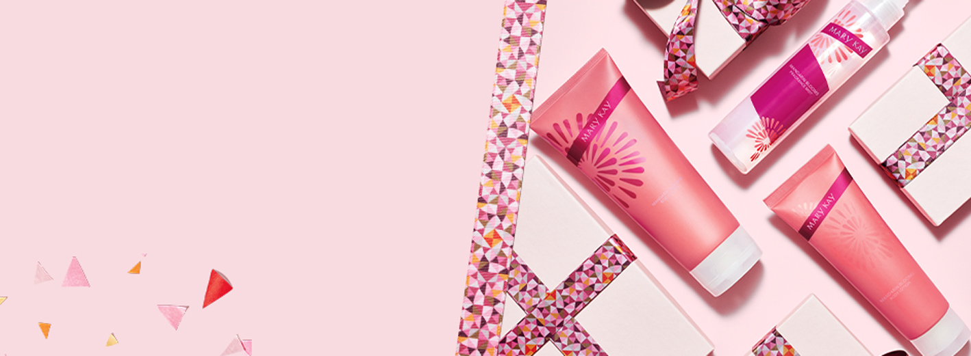Das Mary Kay Mandarin Blooms Body Care Set liegt zwischen rosa Geschenkverpackungen und Schleifenband