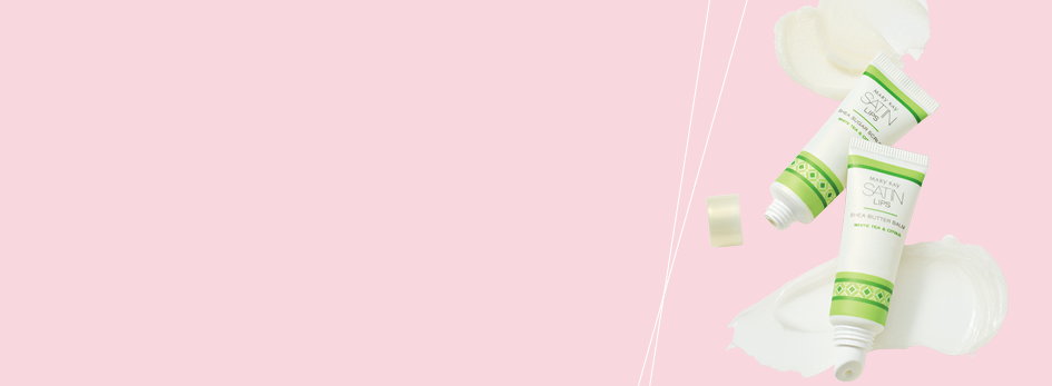 Das Mary Kay Satin Lips Pflegeset liegt auf einem rosa Hintergrund mit Produktkleksen.