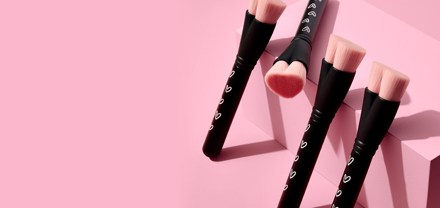 Vier Mary Kay Heart-Shaped Foundation Brushes – schwarze Pinsel zum Auftragen von Make-up mit rosa Pinselhaaren in Herzform, für die Mary Kay bei jedem Verkauf an FLY & HELP spendet.