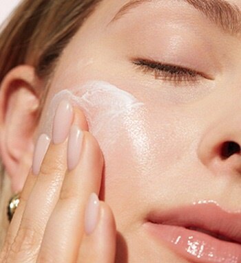 Woman rubbing facial cleaner on cheek