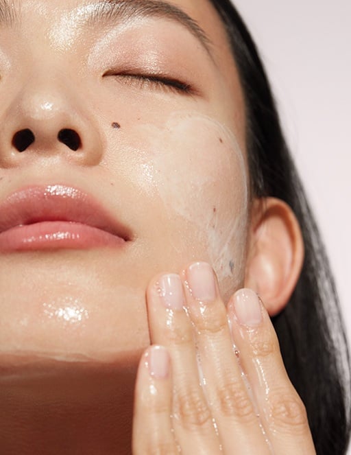 Eine Frau trägt mit der Hand ein Reinigungsprodukt (Mary Kay Cleanser) auf ihr Gesicht auf und hat dabei die Augen geschlossen