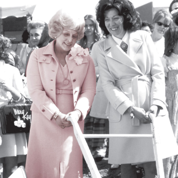 Auf einem alten Foto sind im Vordergrund zwei Frauen zu sehen - links Mary Kay Ash, die Firmengr&uuml;nderin des Direktvertriebsunternehmens Mary Kay, in einem rosa Kost&uuml;m. Im Hintergrund viele weitrere Frauen.