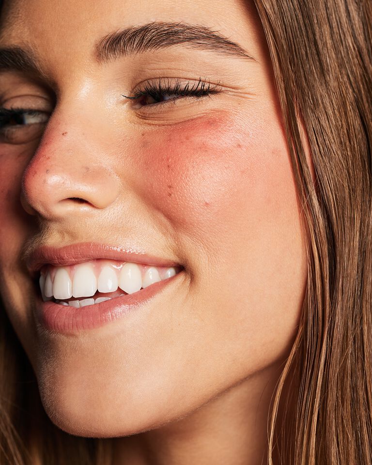 Nahaufnahme einer Frau, die den Strawberry Makeup Trend tr&auml;gt: Glowy skin, Fake Freckles und sonnengek&uuml;sste Wangen