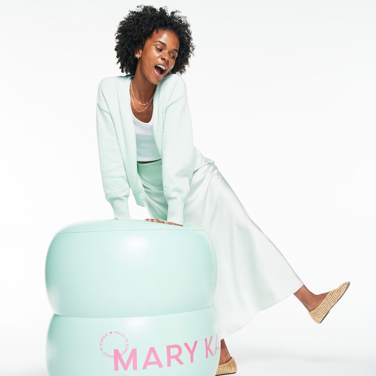 Eine Frau sitzt auf einem &uuml;bergro&szlig;en Tiegel des Mary Kay&reg; Melt-In Cleansing Balm