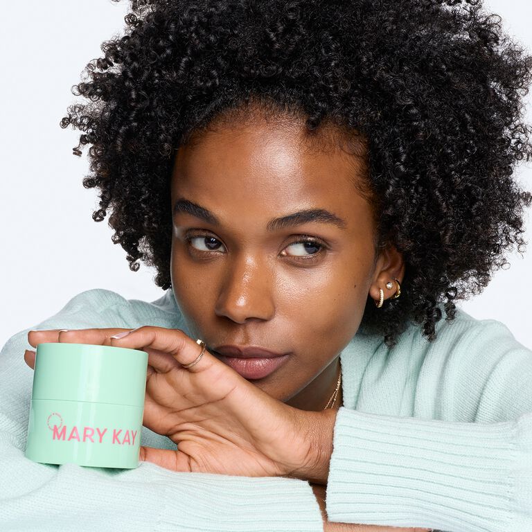 Eine Frau hinter einem gr&uuml;nen Tiegel des Mary Kay&reg; Melt-In Cleansing Balm