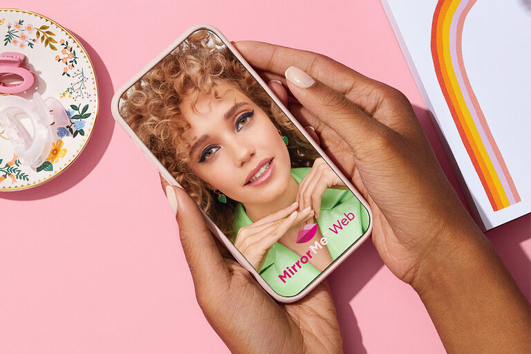 Eine Frau probiert MirrorMe (virtuell Make-up Produkte auftragen) am Handy aus.