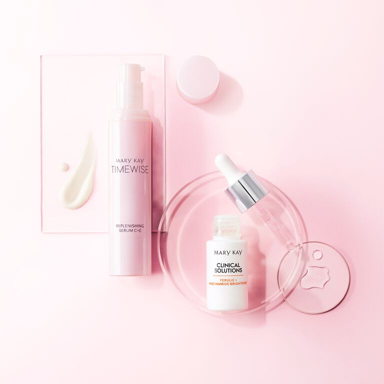 Mary Kay TimeWise Replenishing Serum und Clinical Solutions Brightener auf rosa Hintergrund.
