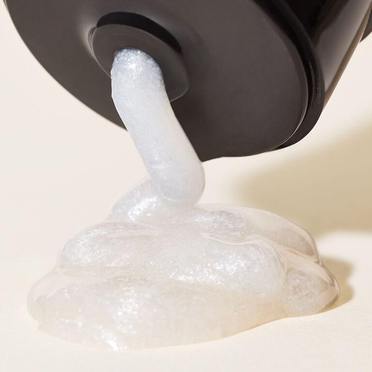 Nahaufnahme: Aus einer schwarzen Tube wird eine kleine Menge des wei&szlig;en MK Men Invigorating Face Scrub Gesichtspeeling von Mary Kay herausgedr&uuml;ckt. Es sind kleine Peelingk&uuml;gelchen zu sehen.
