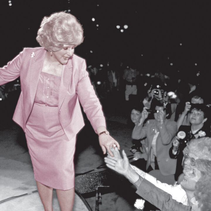 Auf einem alten Foto ist Mary Kay Ash, die Firmengr&uuml;nderin des Direktvertriebsunternehmens Mary Kay, in einem rosa Kost&uuml;m auf einer Art B&uuml;hne zu sehen. Sie ist umringt von Menschen, die ihr zujubeln oder Fotos machen. Sie reicht zwei Frauen die Hand.
