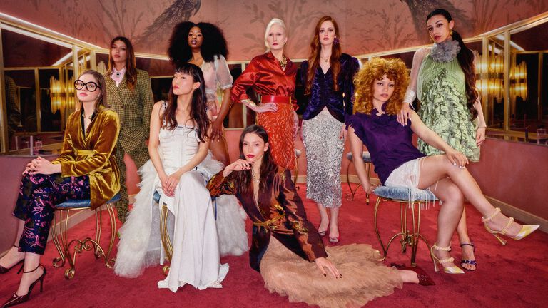 Einige Frauen in schicken Outfits sitzen und stehen in einem Ankleidezimmer
