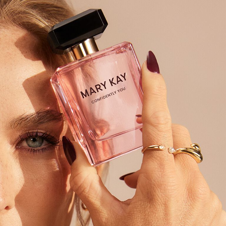 Eine Frau h&auml;lt den Mary Kay Confidently You Parf&uuml;mflakon neben ihr Gesicht