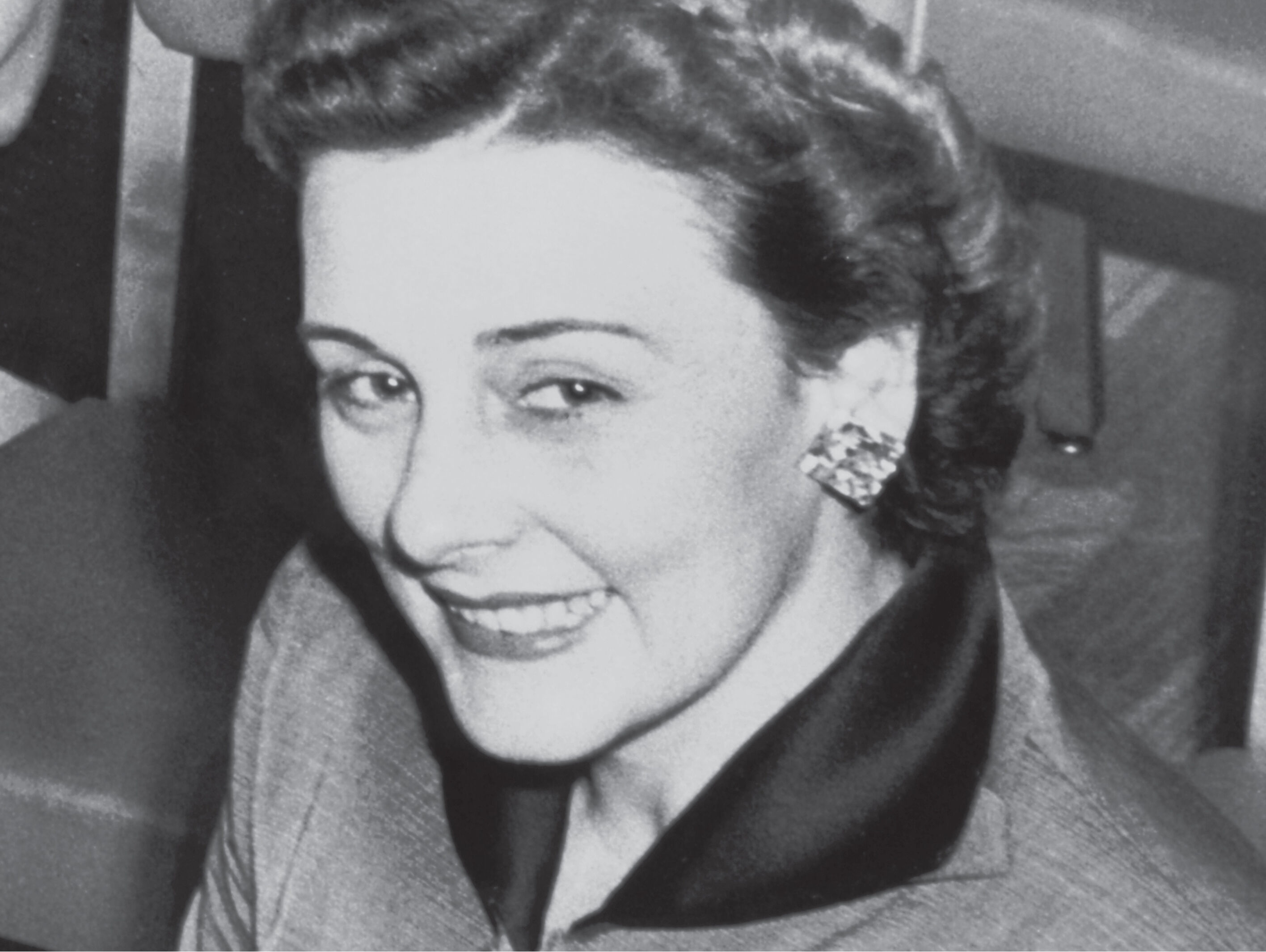 Vintage-Foto der Mary-Kay-Gr&uuml;nderin in einem eleganten Anzug und auff&auml;lligen Ohrringen.