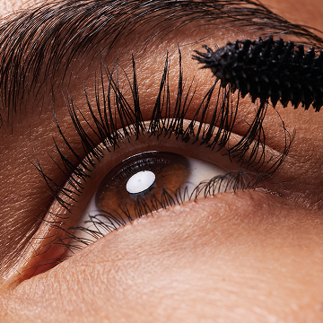 Nahaufnahme: An den Wimpern einer Frau wird Mascara aufgetragen