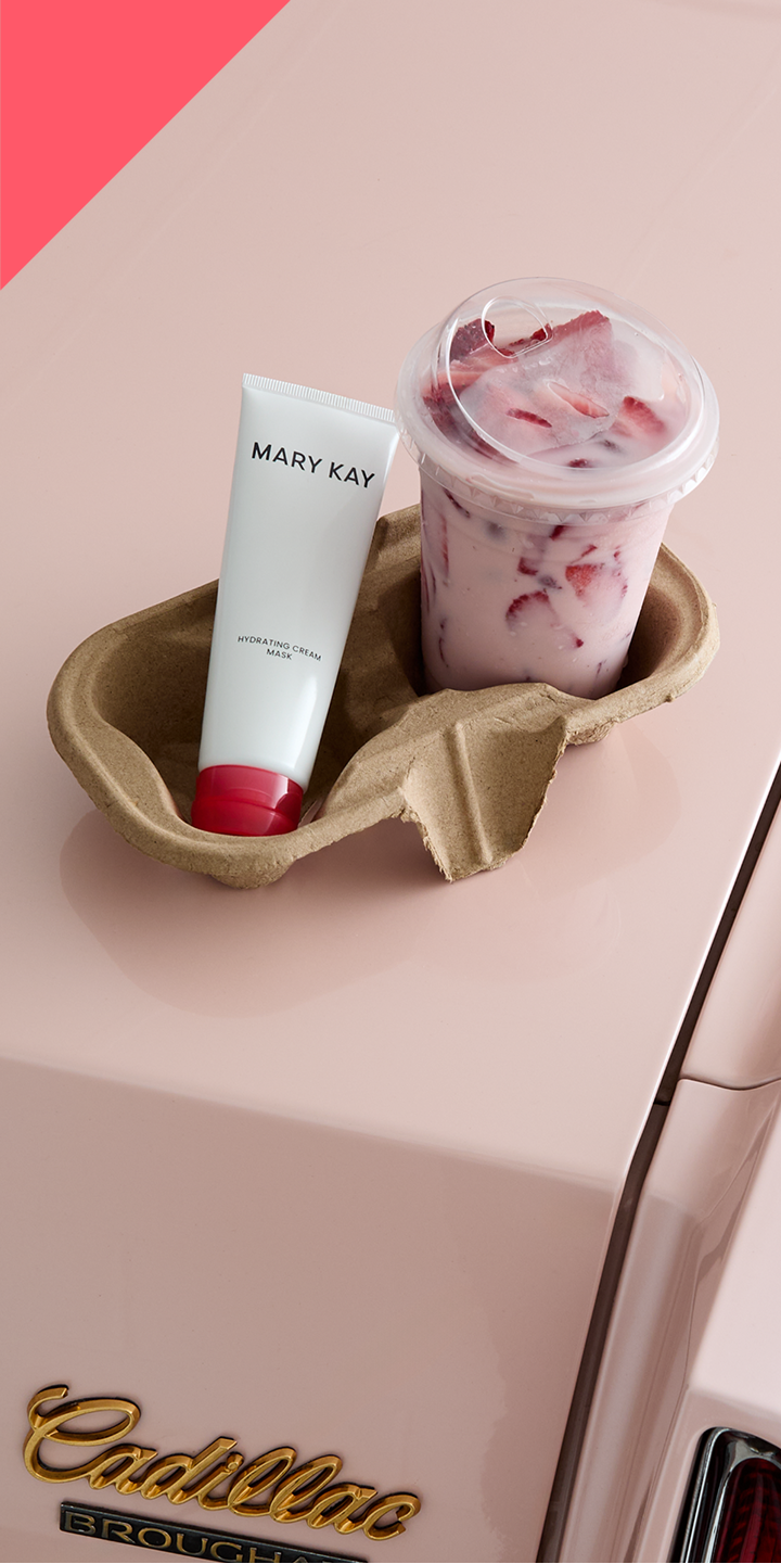 Ein Cup Carrier (Papp-Bechertr&auml;ger) mit zwei F&auml;chern ist gef&uuml;llt mit einem rosa Getr&auml;nk mit roten Erdbeeren sowie der wei&szlig;-roten Tube der Mary Kay Hydrating Cream Mask