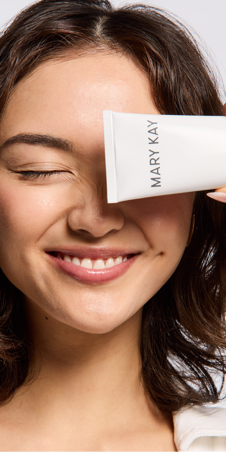 Nahaufnahme einer Frau, die sich die Tube der Mary Kay Hydrating Cream Mask &uuml;ber das eine Auge h&auml;lt und das andere Auge geschlossen hat