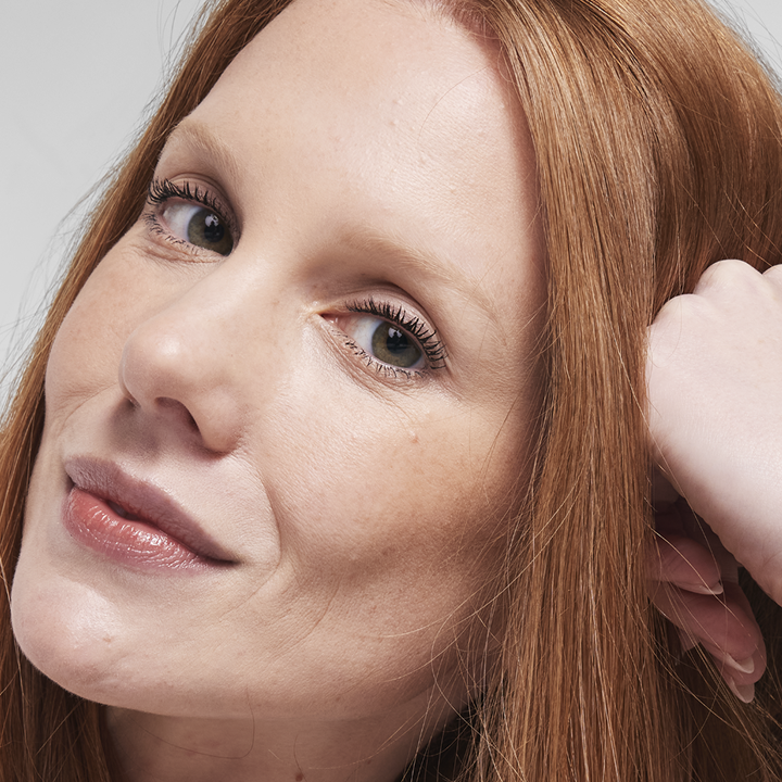 Eine Frau mit hellem Hautton blickt in die Kamera und tr&auml;gt die TimeWise&reg; Luminous 3D Foundation mit strahlendem Finish.