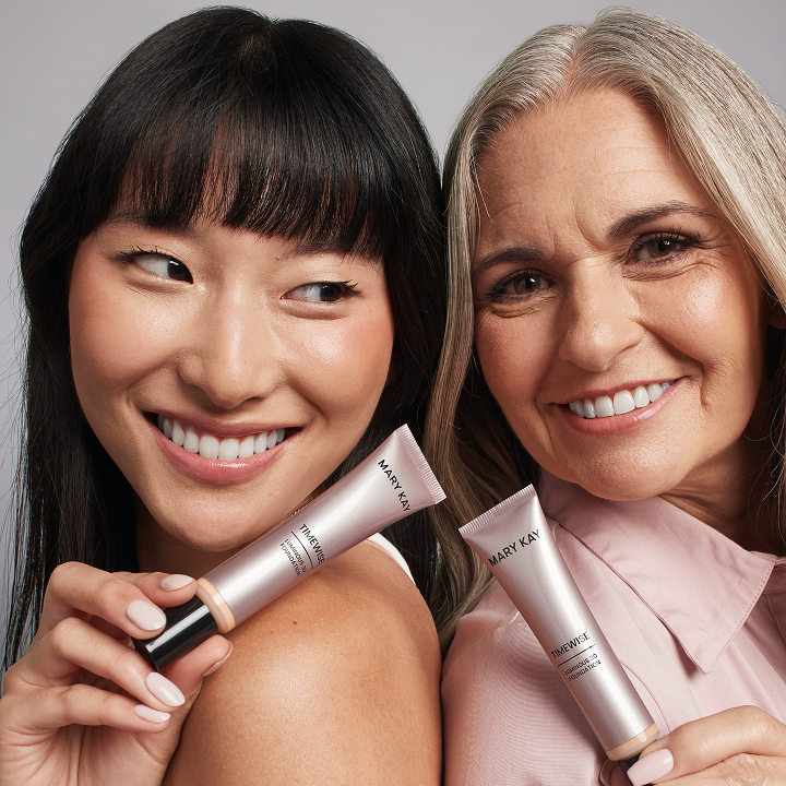 Zwei Frauen mit unterschiedlichen Hautt&ouml;nen halten die TimeWise&reg; Luminous 3D Foundation und blicken in die Kamera.