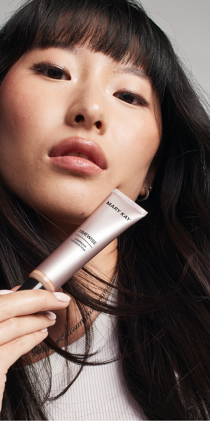 Eine Frau h&auml;lt die TimeWise&reg; Luminous 3D Foundation und blickt selbstbewusst in die Kamera.